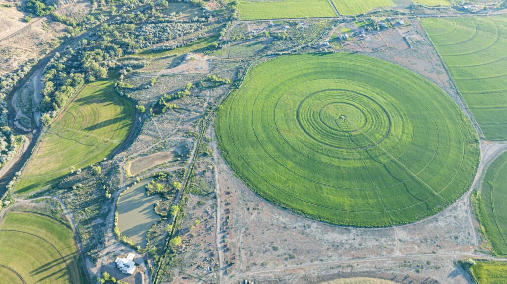 Aerial View of Lush, Central Pivot Crops, amidst Expansive Agricultural Farmland, with Improvements, Ponds and the Gunnison River- North Fork River Ranch