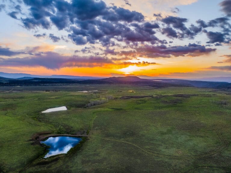 Picturesque View of Telluride Mesa Ranch, featuring 2080± Acres of Lush Landscape and distant Mountains, under beautiful sunset light- A Colorado Ranch For Sale